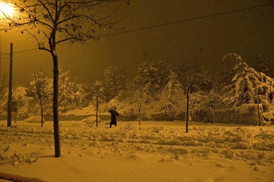 pedestrian walks on a snow-covered street early morning in Jerusalem