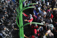 Migrants plea to Mexican National Guardsmen at the border crossing between Guatemala and Mexico in Tecun Uman, Guatemala, Saturday, Jan. 18, 2020. More than a thousand Central American migrants surged onto the bridge spanning the Suchiate River, that marks the border between both countries, as Mexican security forces attempted to impede their journey north. (AP Photo/Marco Ugarte)