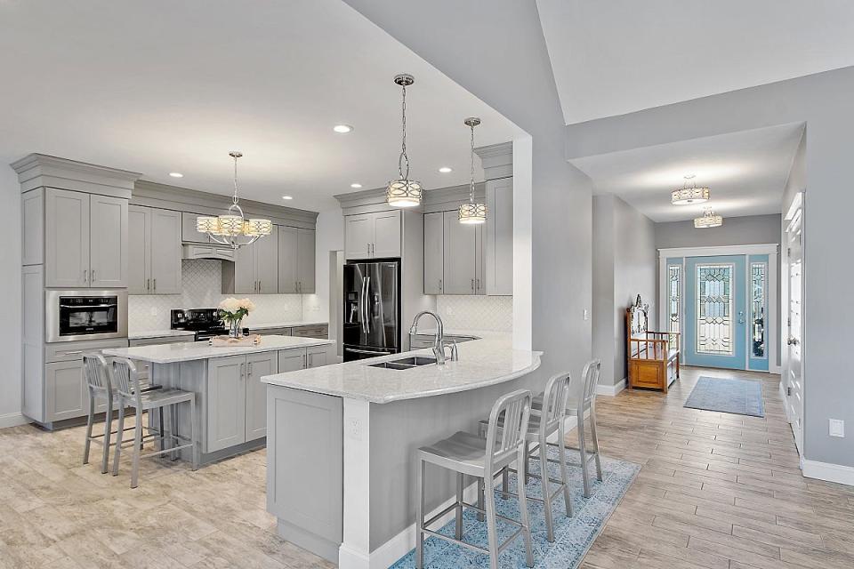 The kitchen features Cambria quartz countertops, black stainless-steel appliances, a wine chiller, center island with seating and a peninsula with additional seating.