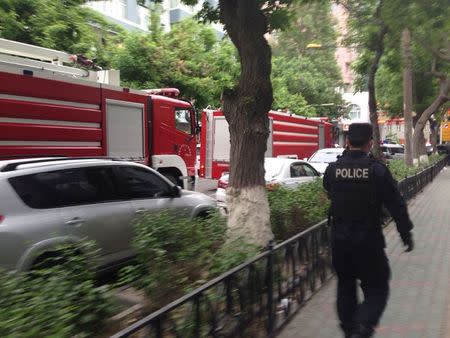 A policeman and fire-fighting trucks are seen near the site of an explosion, which has been cordoned off, in downtown Urumqi, Xinjiang Uighur Autonomous Region, May 22, 2014 in this photo distributed by China's official Xinhua News Agency. REUTERS/Cao Zhiheng/Xinhua