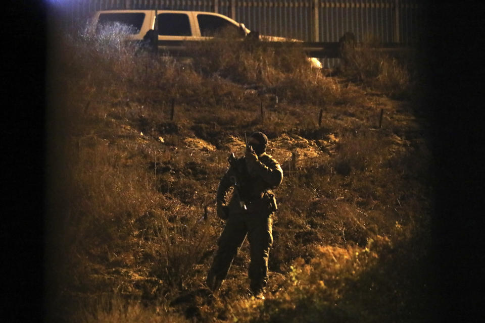 A U.S. Border Patrol agent keeps an eye on a group of Honduran migrants standing near the border wall as seen from Tijuana, Mexico, Friday, Nov. 30, 2018. The group eventually crossed and were immediately detained. Thousands of migrants who traveled via a caravan members want to seek asylum in the U.S. but may have to wait months because the U.S. government only processes about 100 of those cases a day at the San Ysidro border crossing in San Diego. (AP Photo/Felix Marquez)