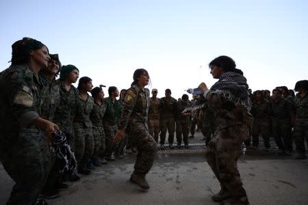 Syrian Democratic Forces (SDF) female fighters dance during a graduation ceremony in the city of Hasaka, northeastern Syria, August 9, 2017. REUTERS/Rodi Said