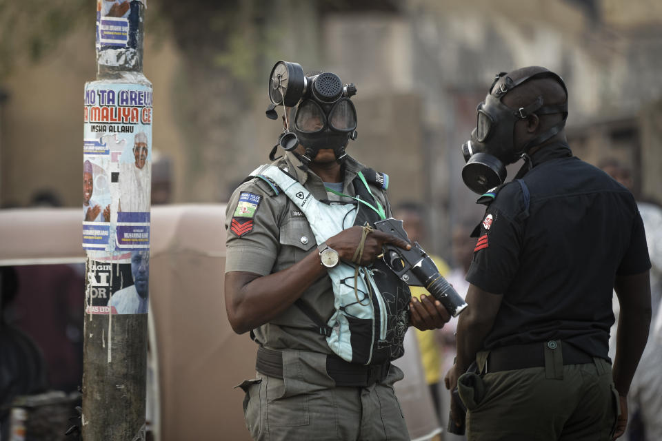 Riot policeman wear gas masks and carry a tear gas grenade launcher, but did not fire, during a celebratory gathering of supporters of President Muhammadu Buhari anticipating victory, in Kano, northern Nigeria Monday, Feb. 25, 2019. Nigeria's electoral commission on Monday began announcing official results from the country's 36 states as President Muhammadu Buhari seeks a second term. (AP Photo/Ben Curtis)