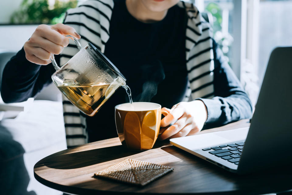 a woman pouring tea into her mug