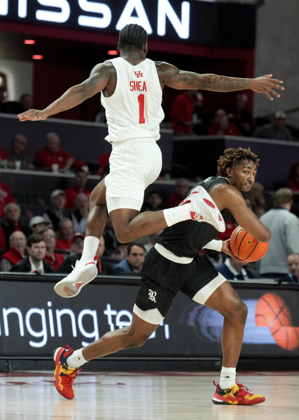 Houston guard Jamal Shead (1) leaps past Rice guard Mekhi Mason (2) during the first half of an NCAA college basketball game at the Fertitta Center, Wednesday, Dec. 6, 2023, in Houston. (Jason Fochtman/Houston Chronicle via AP)