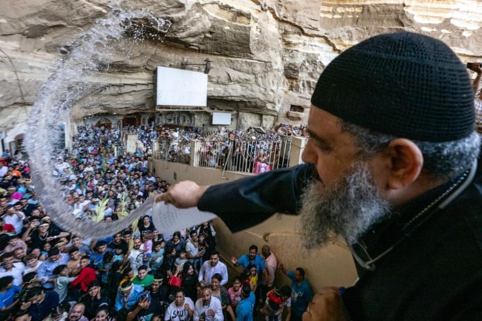 Coptic Orthodox priest sprinkles holy water on gathered worshippers.