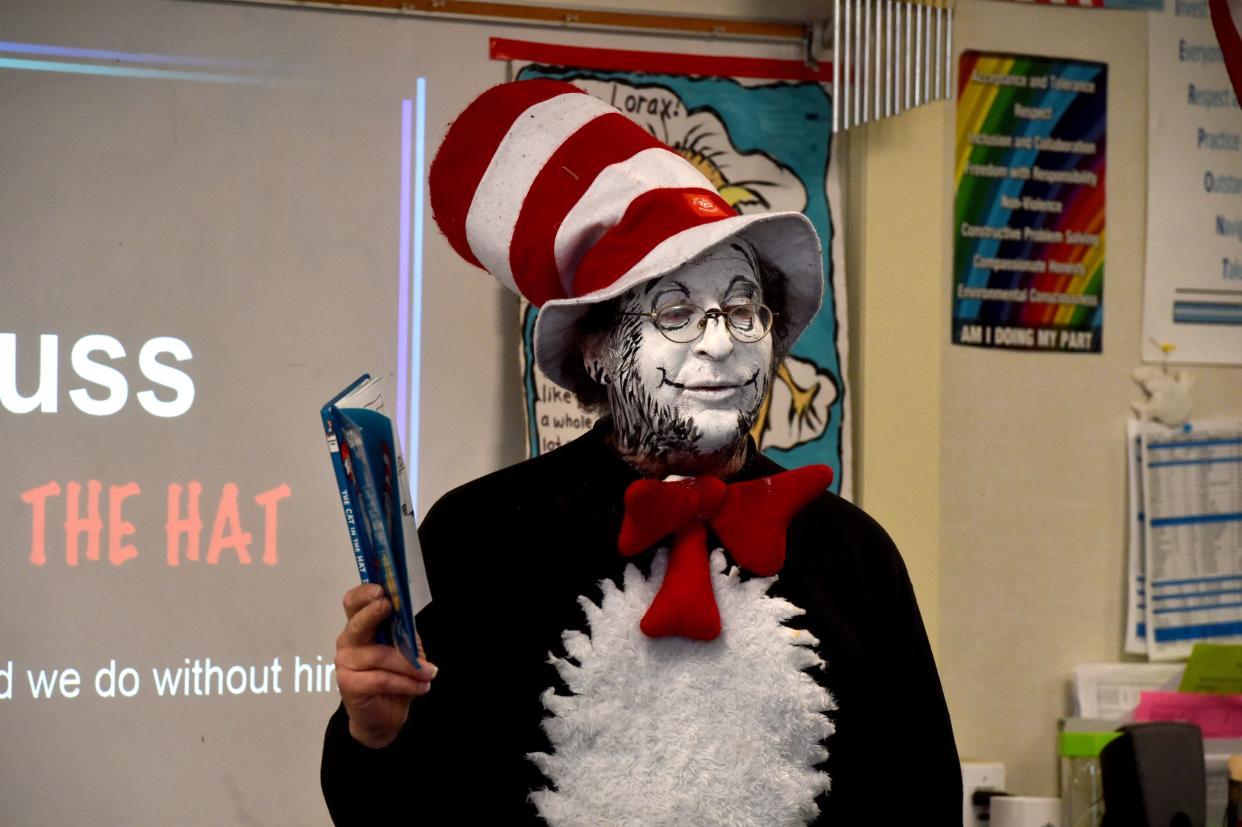 A third-grade teacher reads a Dr. Seuss book to his class.