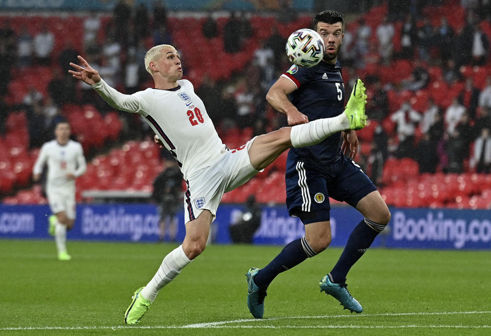 England's Phil Foden, left, and Scotland's Grant Hanley challenge for the ball during the Euro 2020 soccer championship group D match between England and Scotland at Wembley stadium in London, Friday, June 18, 2021. (Justin Tallis/Pool via AP)