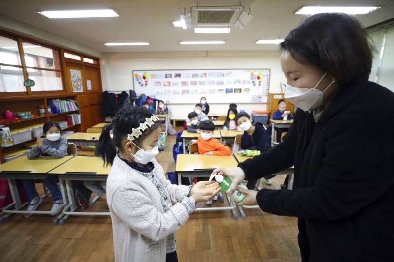 武漢肺炎疫情升高，南韓首爾的小學老師正為同學消毒。（美聯社）