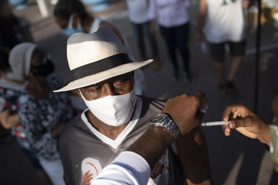 FILE - In this March 24, 2021, file photo, a man gets his dose of the Sinovac vaccine at a COVID-19 vaccination point for seniors in Duque de Caxias, Brazil. April is shaping up to be Brazil’s darkest month yet in the pandemic. Hospitals are struggling to absorb a crush of patients, deaths are on track to hit record highs and there are few signs of a reprieve from problems besetting the country's vaccination program. (AP Photo/Silvia Izquierdo, File)