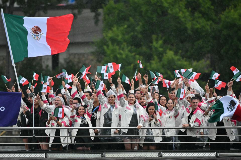 Athletes from Mexico's delegation wave flags as they sail on a boat along the river Seine during the opening ceremony of the Paris 2024 Olympic Games in Paris on July 26, 2024. (Photo by Miguel MEDINA / AFP) (Photo by MIGUEL MEDINA/AFP via Getty Images)