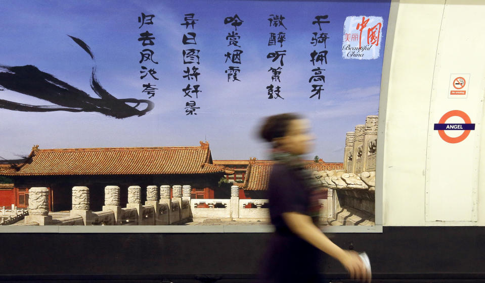 In this photo taken Wednesday, Sept. 4, 2013, a commuter walks in front of a poster for the China National Tourist Office that's part of its "Beautiful China" campaign on display at the Angel tube station in Islington, London. China's new tourism slogan "Beautiful China" has been criticized by industry experts who say it illustrates a marketing problem that has led to a weakness in growth in foreign visitors over the past few years. The Chinese characters in black are a North Song Dynasty poem by Liu Yong that describes nobles enjoying beautiful scenes while riding on horse. (AP Photo/Alastair Grant)