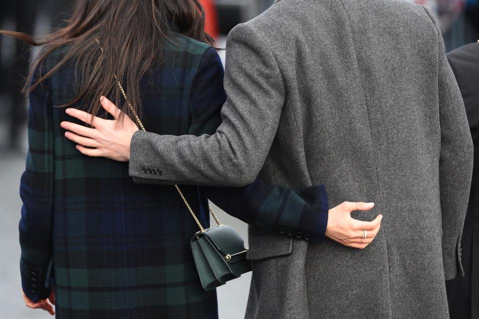 Prince Harry and Meghan Markle stand with their arms around each other.