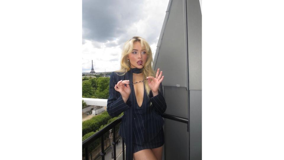 Sabrina Carpenter poses in a mini skirt and waistcoat in front of the EiffelTower