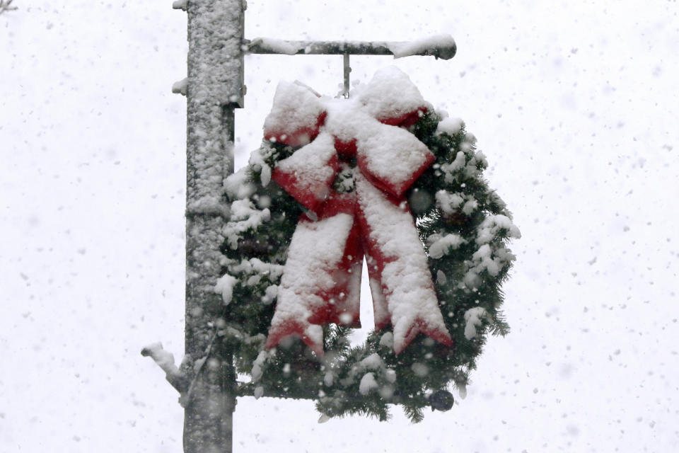 Snow clings to a holiday wreath, Saturday, Dec. 5, 2020, in downtown Marlborough, Mass. The northeastern United States is seeing the first big snowstorm of the season. (AP Photo/Bill Sikes)