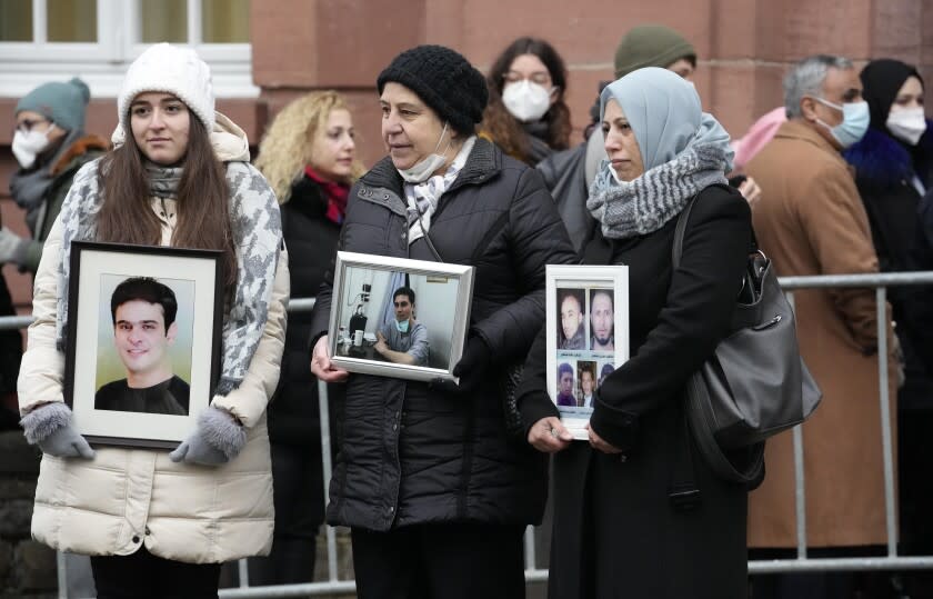From left, Syrian women Samaa Mahmoud, Mariam Alhallak and Yasmen Almashan hold pictures of relatives who died in Syria, before the verdict in front of the court in Koblenz, Germany, Thursday, Jan. 13, 2022. A German court has convicted a former Syrian secret police officer of crimes against humanity for overseeing the abuse of detainees at a jail near Damascus a decade ago. The verdict Thursday in the landmark trial has been keenly anticipated by Syrians who suffered abuse or lost relatives in the country's long-running conflict. (AP Photo/Martin Meissner)