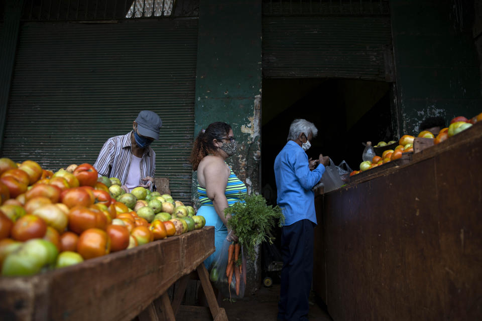 Yuliet Colon, center, waits to check-out at an agricultural market near her home, in Havana, Cuba, Friday, April 2, 2021. Colon is among several Cubans who, with more ingenuity than resources, help their compatriots cope with shortages exacerbated by the new coronavirus pandemic with Facebook posts of culinary creations designed around what they're actually likely to find at the market or with government rations. (AP Photo/Ramon Espinosa)