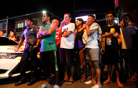 Residents watch the body of a man (not pictured), who police said was killed in a spate of drug related violence overnight in Manila, Philippines August 16, 2017. REUTERS/Dondi Tawatao