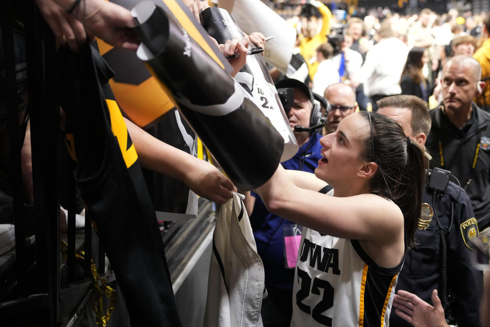 Iowa guard Caitlin Clark (22) signs autographs after the team's win over Michigan in an NCAA college basketball game Thursday, Feb. 15, 2024, in Iowa City, Iowa. Clark set a new NCAA women's career scoring record. (AP Photo/Matthew Putney)