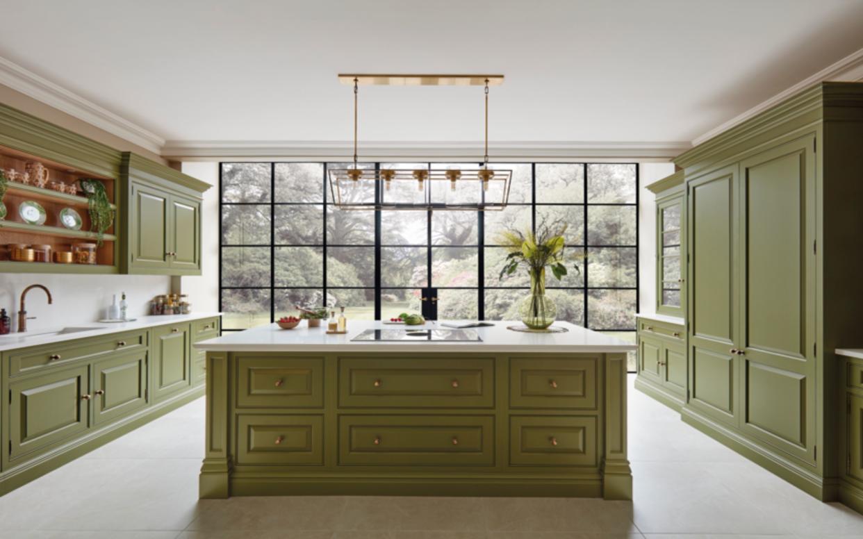  Green kitchen with island and white marble worktops. 