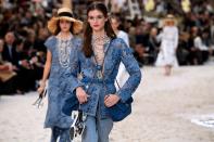 <p>Dieser edle Denim-Look aus einem floralen Blazer, sowie einer Boyfriend-Jeans im Used-Look wurde getoppt durch verspielte Perlenketten. Auch dieses Model trug zwei dazu farblich passende Taschen mit den typischen Chanel-Schulterriemen aus Kettengliedern. (Bild: Getty Images) </p>