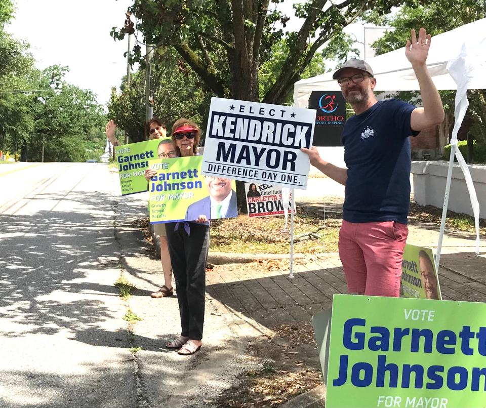 From left, Angel Croft, Mary Dixon and Andrew Goss wave signs for Augusta mayoral candidates Garnett Johnson and Steven Kendrick at the Asbury United Methodist Church polling place Tuesday.