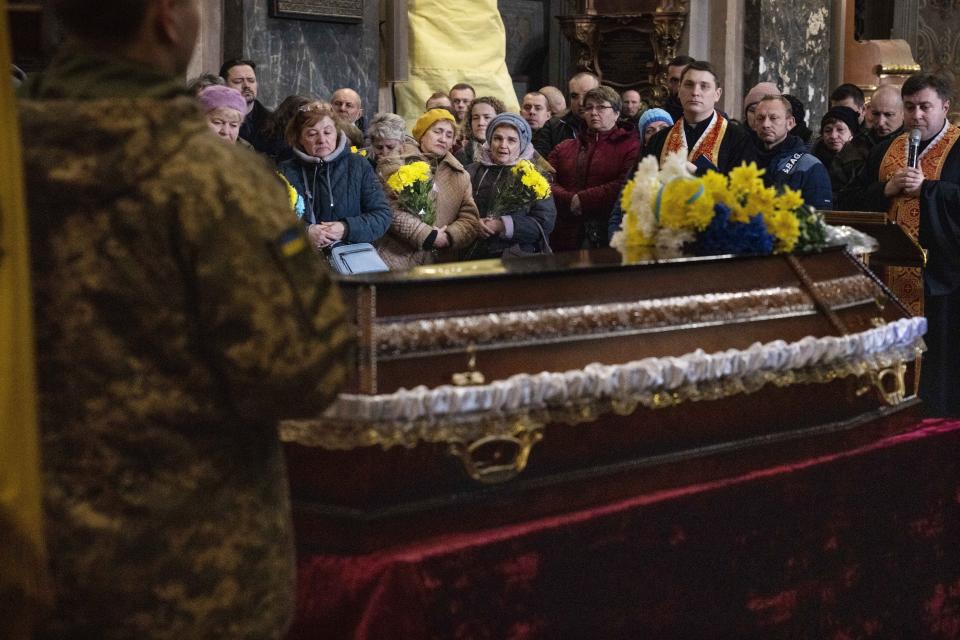 People stand in front of the coffin of 40-year-old Senior lieutenant Oliynyk Dmytro, killed in action, during his funeral ceremony in the Holy Apostles Peter and Paul Church, in Lviv, western Ukraine, Saturday, April 2, 2022. (AP Photo/Nariman El-Mofty)