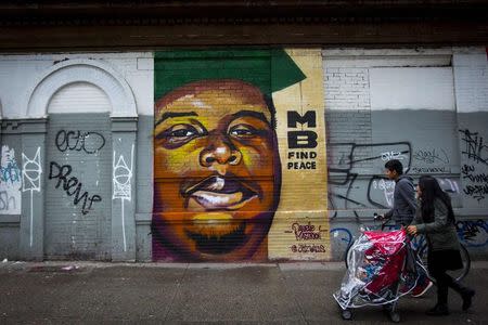 People walk past a mural of Michael Brown in the Bushwick neighborhood of Brooklyn in New York November 27, 2014. Brown was shot to death by police officer Darren Wilson on August 9 in Ferguson, Missouri. REUTERS/Andrew Kelly