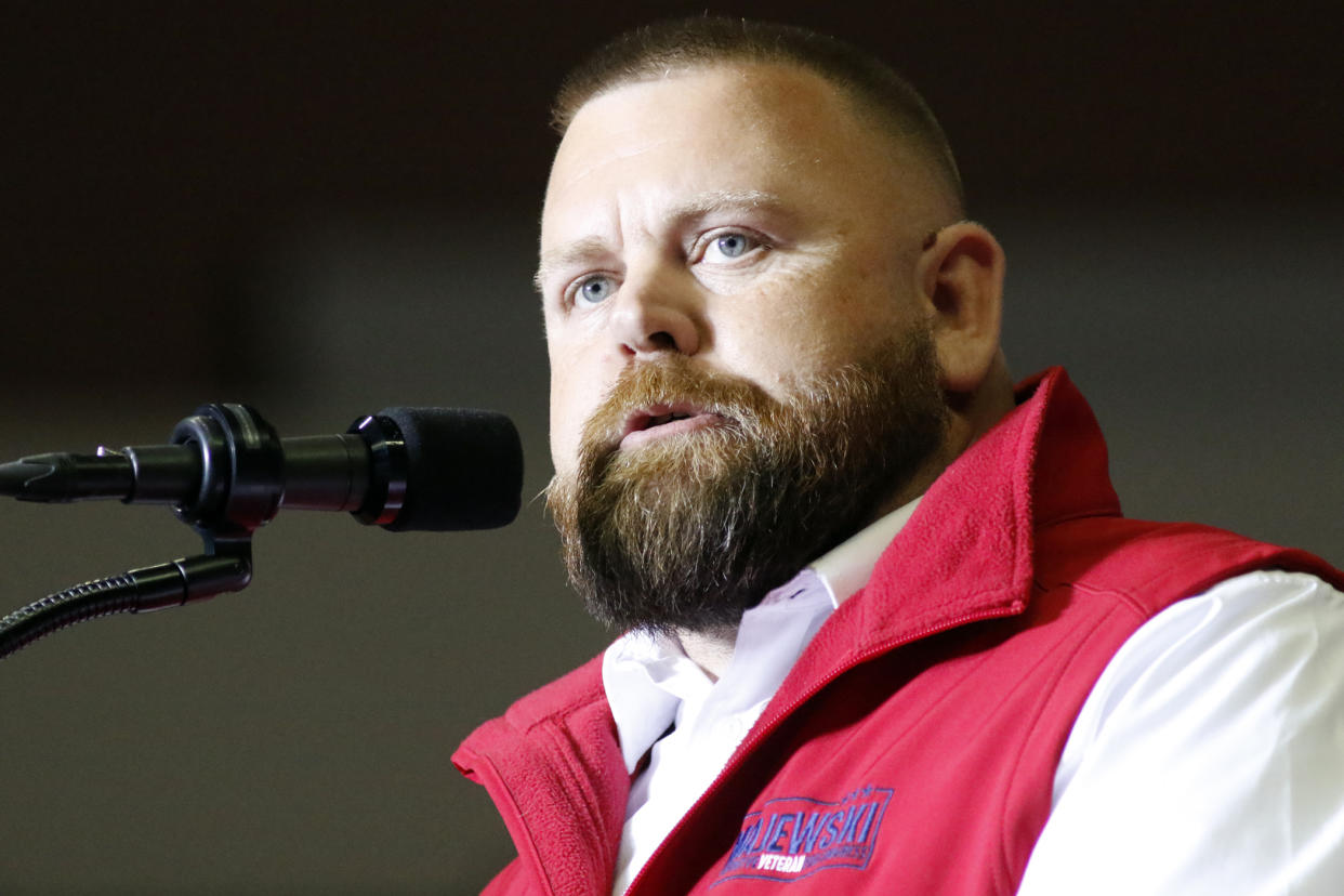 J.R. Majewski at the microphone, in shirtsleeves and a bright-red vest with his name on it.