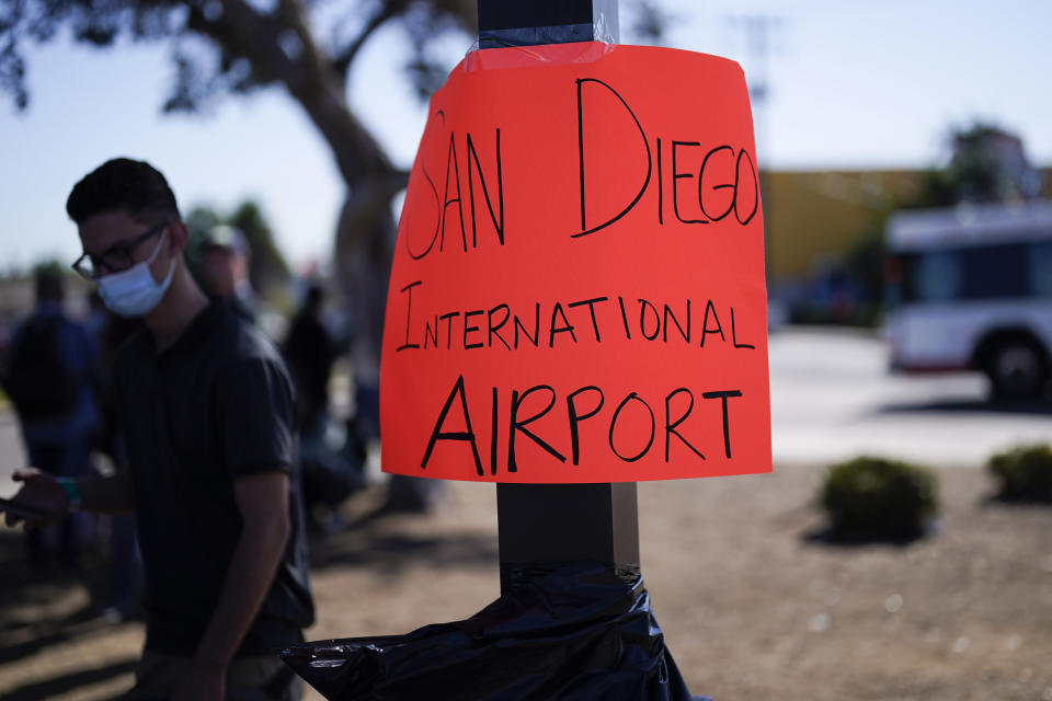 A sign for the airport sits in a parking lot set up to help migrants with travel plans, accommodation, food and shelter, Friday, Oct. 6, 2023, in San Diego. San Diego's well-oiled system of migrant shelters is being tested like never before as U.S. Customs and Border Protection releases migrants to the streets of California's second-largest city because shelters are full. (AP Photo/Gregory Bull)