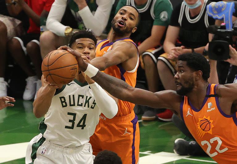 Giannis Antetokounmpo pugna con Deandre Ayton (22) y Mikal Bridges; el griego hizo de todo para el triunfo de Milwaukee Bucks sobre Phoenix Suns por 109-103 que equilibró la final de la NBA.