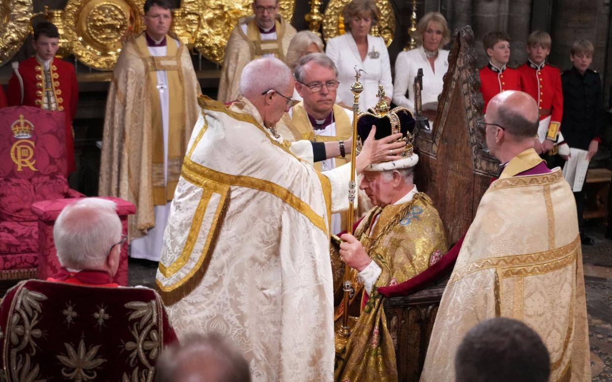The Archbishop places St Edward's Crown on the head of King Charles in Westminster Abbey, with senior church figures looking on
