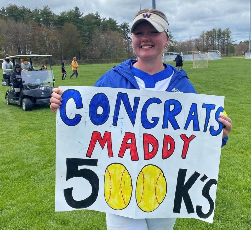 Winnacunnet senior Maddy Eaton holds a congratulatory sign after recording her 500th career strikeout in Saturday's 6-1 win over Oyster River.