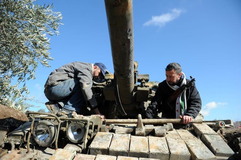 Rebel fighters in al-Yaqubia on February 2, 2013, inspect a Soviet-made tank T-55 abandoned by Syrian regime forces. An offer of talks by Syria's main opposition leader to President Bashar al-Assad suffered setbacks on Tuesday as state media said it was two years too late, and a principal opposing faction flatly rejected the idea