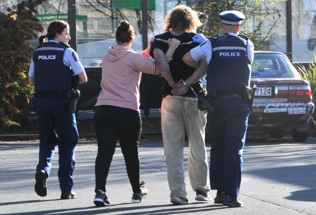 Police take a suspect into custody near the Countdown supermarket in central Dunedin, New Zealand, Monday, May 10, 2021. A man began stabbing people at a New Zealand supermarket Monday, wounding five people, three of them critically, according to authorities. 