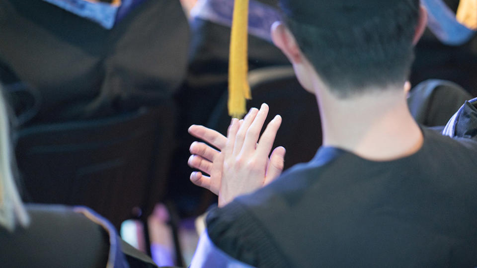 Picture of a student at graduation, clapping