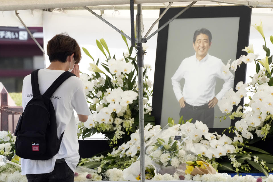 A person offers flowers and prayers for former Prime Minister Shinzo Abe, at Zojoji temple prior to his funeral wake Monday, July 11, 2022, in Tokyo. Abe was assassinated Friday while campaigning in Nara, western Japan. (AP Photo/Eugene Hoshiko)