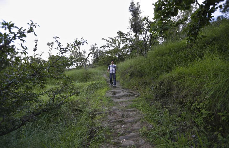 In this Aug. 24, 2012 photo, Bhuwan Butholia, like many of his colleagues, walks through the hilly terrain on his way to and from the B2R center in Simayal, India. Before B2R arrived in Simayal, Butholia used to work in an auto parts factory 150 kilometers (90 miles) away, spending whatever he earned on food and rent. (AP Photo/Saurabh Das)