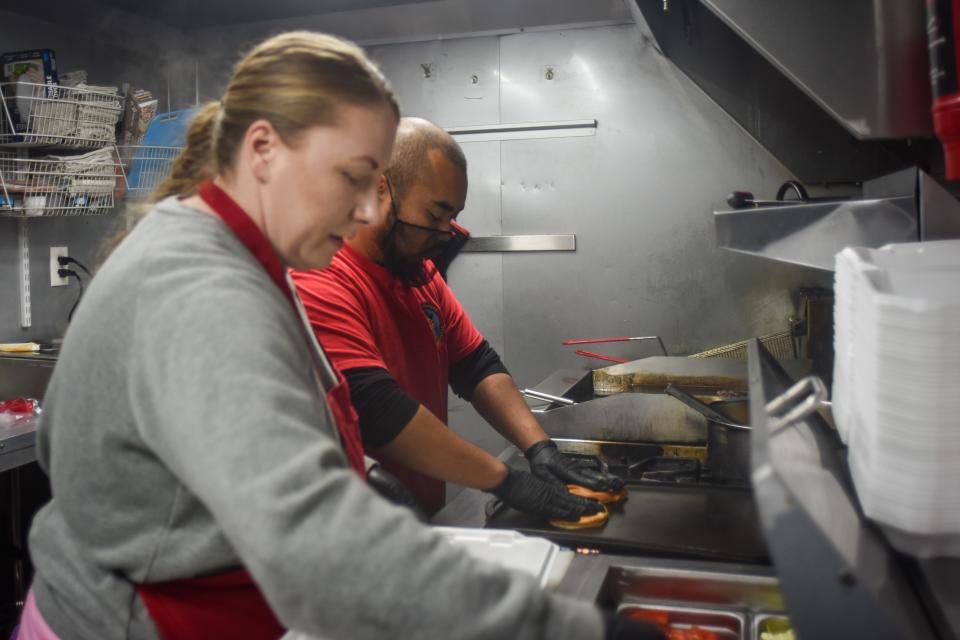 Cheezy Noodle owners Jessica Eck and Ravuth "Johnny" Tahn making burgers for burger battle in their food truck Jan. 25, 2024.