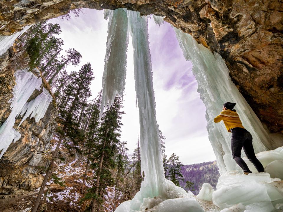 Girl standing under frozen waterfall in South Dakota.