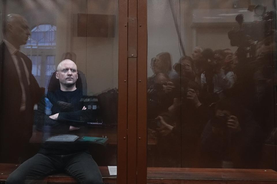 Sergei Udaltsov, Russian left-wing political activist, left, looks at journalists sitting behind a glass in a cage in a courtroom in Moscow, Russia, Friday, Jan. 12, 2024. A Russian state news agency says a Russian court has ordered that a pro-war activist and critic of President Vladimir Putin be remanded into custody until Feb. 15. That's when Sergei Udaltsov will stand trial for charges of "justifying terrorism." (AP Photo/Alexander Zemlianichenko)