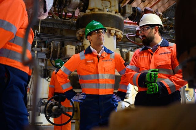 Rishi Sunak in a green hard hat and orange hi vis jacket chats to workers on the Rough 47/3B Bravo gas platform