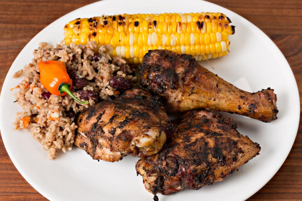 spicy jerk chicken with corn on the cob and rice with a pepper