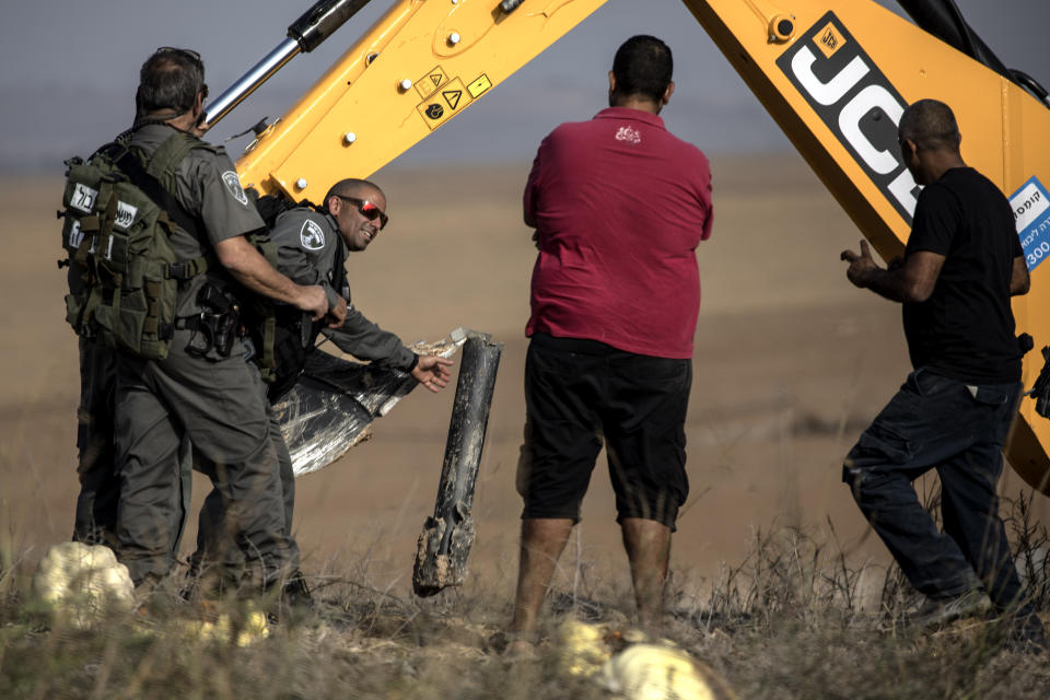 Israeli police sappers remove a rocket fired from the Gaza Strip in farmland near the Israel Gaza border, Wednesday, Nov. 13, 2019. Israeli military said more than 250 rockets have been fired at Israeli communities since the violence erupted following an Israeli airstrike that killed a senior Islamic Jihad commander. (AP Photo/Tsafrir Abayov)