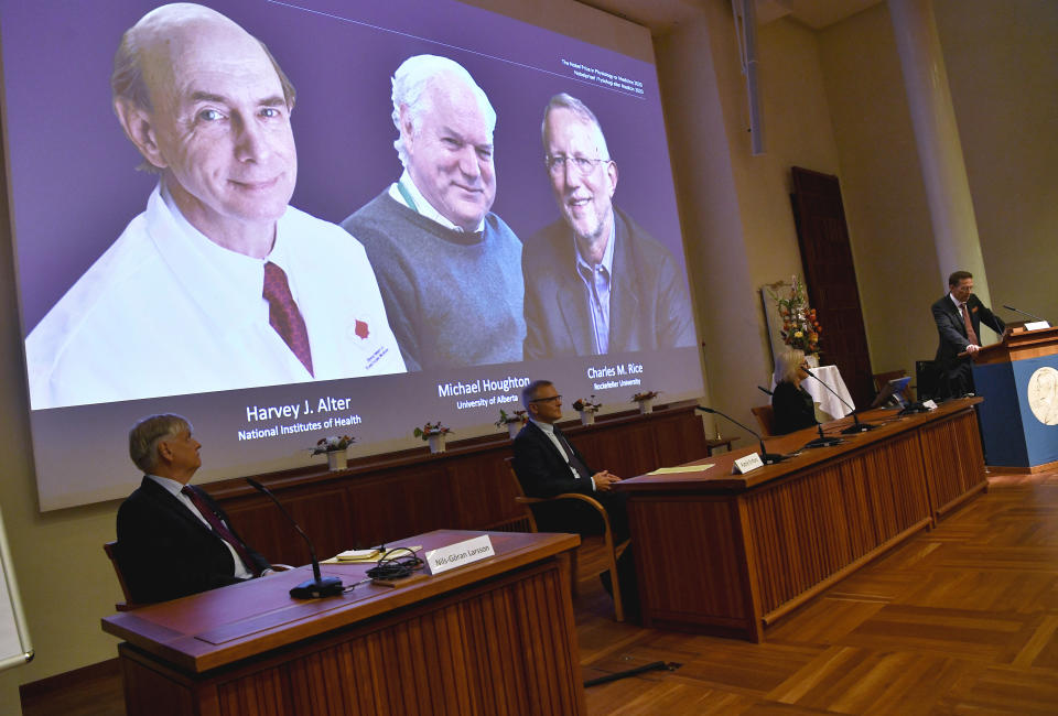 Thomas Perlmann, far right, Secretary of the Nobel Assembly announces the 2020 Nobel laureates in Physiology or Medicine during a news conference at the Karolinska Institute in Stockholm, Sweden, Monday Oct. 5, 2020. The prize has been awarded jointly to Harvey J. Alter, left on screen, Michael Houghton, center, and Charles M. Rice for the discovery of the Hepatitis C virus. (Claudio Bresciani/TT via AP)