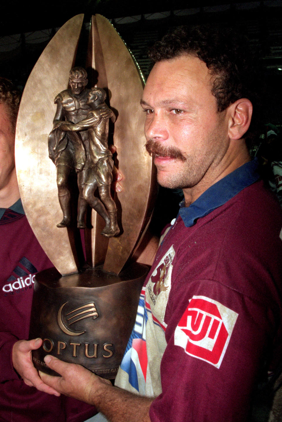 Manly legend Cliff Lyons lifting the NRL trophy.