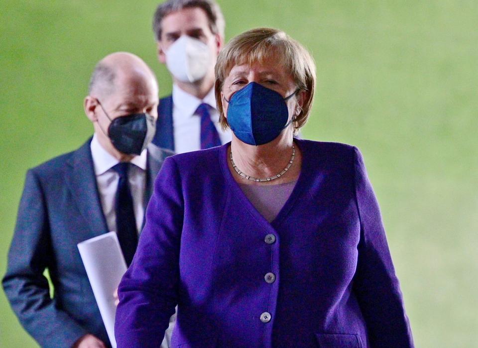 Merkel (right) is pictured arriving at a press conference in front of the current finance minister and expected next chancellor Scholz (left) (AFP)