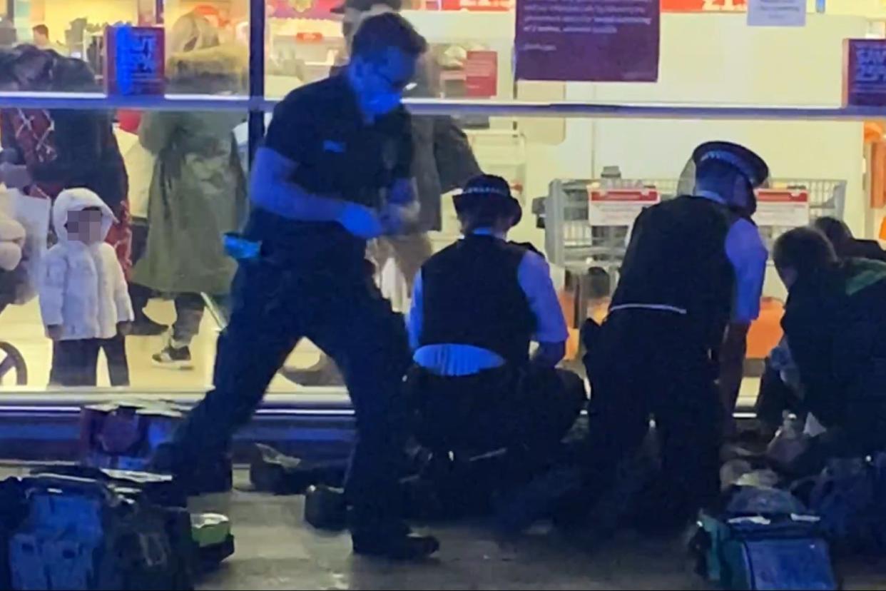 <p>The toddler watches on as paramedics and police battle to save the victim</p> (Claude Atcheba)