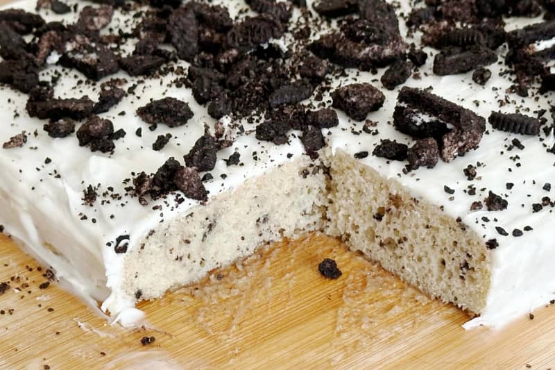 Oreo cake on cutting board with piece cut out.