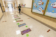 A student runs down a hallway with markers for proper social distancing during the coronavirus outbreak at the Post Road Elementary School, Thursday, Oct. 1, 2020, in White Plains, N.Y. (AP Photo/Mary Altaffer)